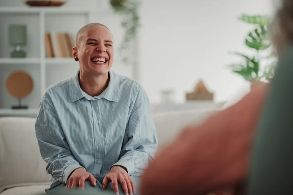 Happy person laughing joyfully while sitting on a white couch