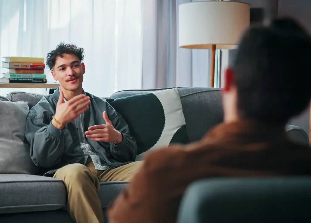 Man in a grey jacket sitting on a couch and talking during a counselling session